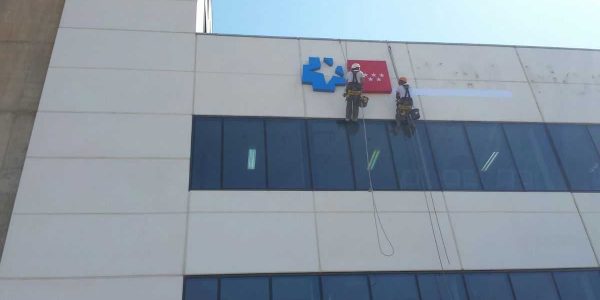 Momento del montaje sobre el muro de los logos luminosos de la Comunidad de Mdrid y el servicio de salud